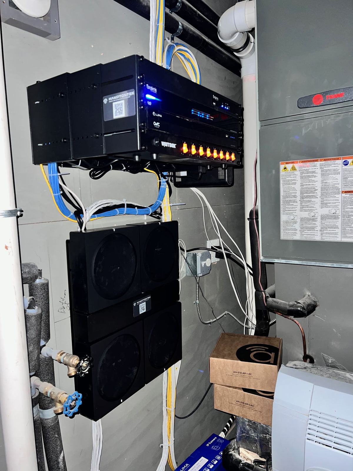 Low-voltage head end: network switch, amplifiers and structured cabling neatly mounted on a wall