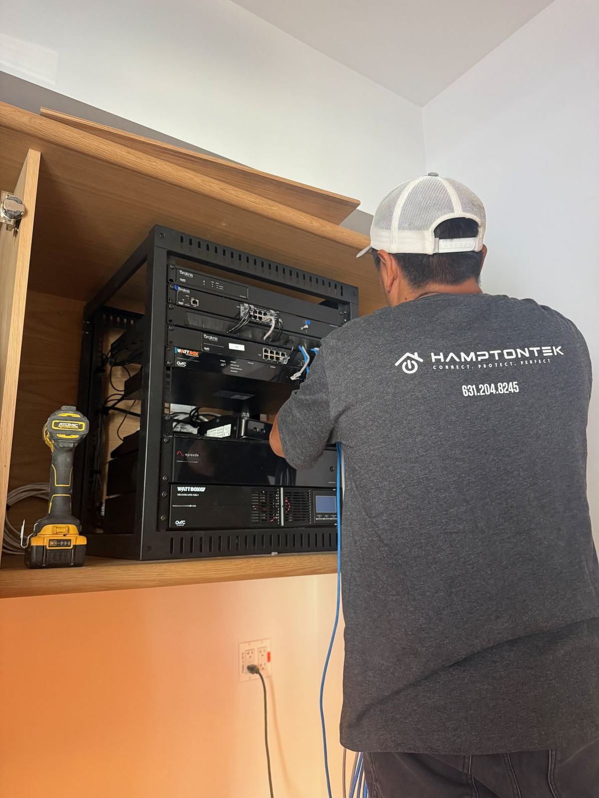 HamptonTek technician installing an equipment rack inside custom cabinetry
